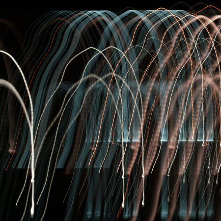 Abstract colored trails of blue and red lights on the night city backgroundの写真素材
