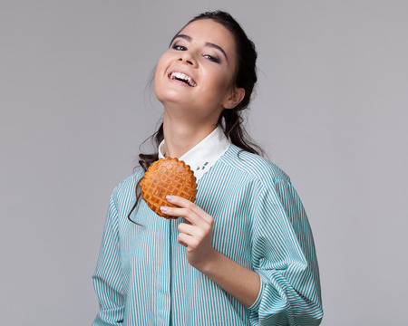 Young brunette woman with a cookie in the hand, toothy smile isolated on white backgroundの写真素材