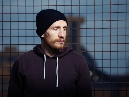 Portrait of a brutal man in a black hat , gloaming, metal grid backgroundの写真素材