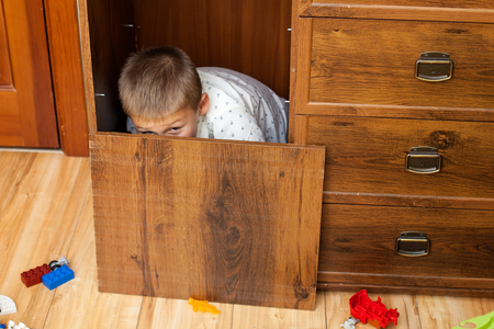 Little boy is hiding in the cupboard in the playroomの写真素材