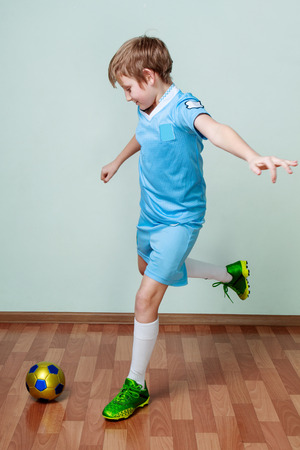 Children activity. Little boy in a blue uniform playing football at the gymの写真素材