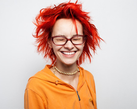 People. Expressions. Portrait of a young beautiful smiling  redheaded  girl in glasses with closed eyes, isolated on white backgroundの写真素材