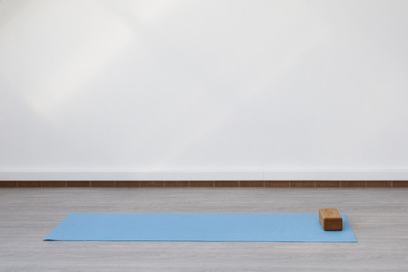 Mat and supporting unit for yoga and fitness lying on the floor. The room is flooded with daylight sunlight from the window, the glare on the white wall.の写真素材