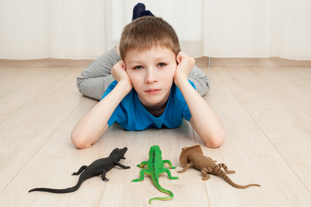Close up a lonely boy laying on the floor with some toys, looking sadの写真素材