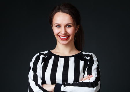 Young brunette woman  in black and white shirt with bright lipstick and beautiful smile, gray backgroundの写真素材