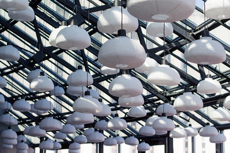 Lot's of white paper lamps on the glass ceiling in a modern building
