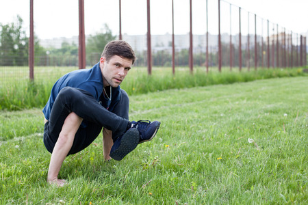 Outdoor yoga workout. Young man doing an exercise in the city park