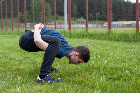 Outdoor yoga workout. Young man doing an exercise in the city park