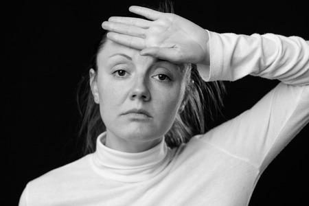 Headache. Close up portrait of a sad woman, holding the hand on the forehead, looking down, isolated...
