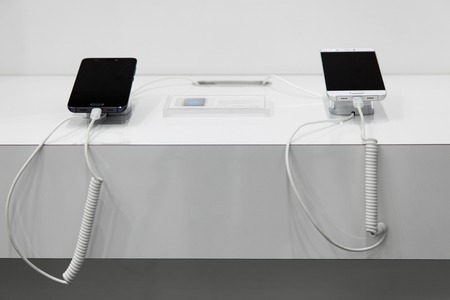 Two  smartphones on a white showcase with  antitheft system