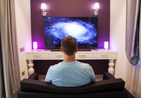 Man watching 4K TV in the living room, view from the backの写真素材