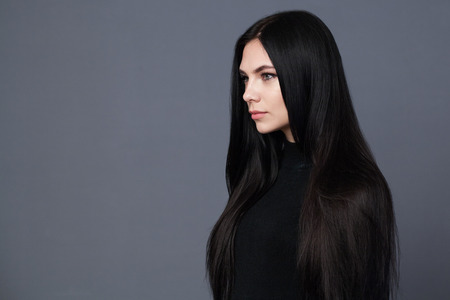 Beautiful brunette woman with well-groomed long hair, gray backgroundの写真素材