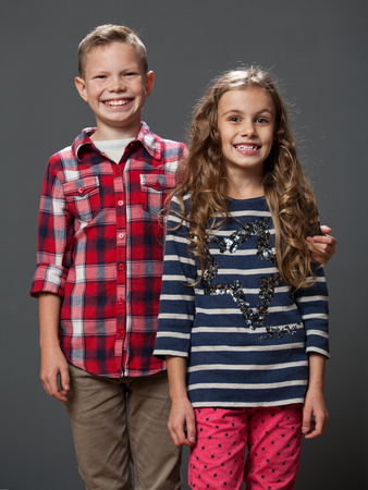 Smiling children - the boy hugging the girl, gray background