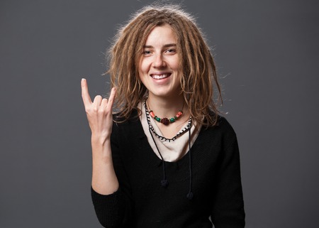 Beautiful smiling hipster woman with dreadlocks, gray background