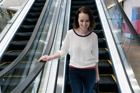 Smiling woman is going down the escalatorの写真素材