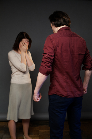 Family abuse, woman is crying, man is menacingly hanging over herの写真素材