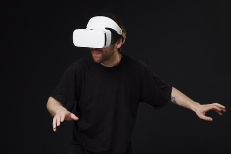 Young man in vr headset moving in virtual reality, black backgroundの写真素材