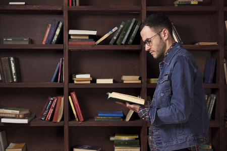 Young man reading a book in the libraryの写真素材