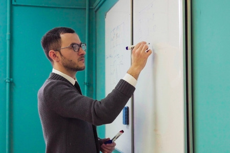 Man teacher writes on whiteboard in university classroomの写真素材