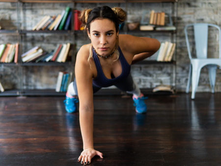 Young fitness woman doing push ups exercise on one hand on floorの写真素材