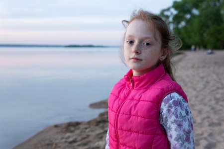 Beautiful pensive teen girl with freckles by sea at sunsetの写真素材