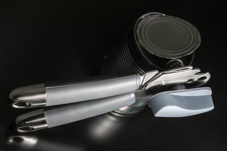 Metal Can Opener with Opened Tin on Dark Backgroundの写真素材