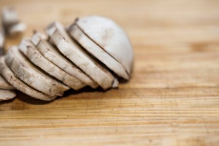 Chopped mushrooms on a chopping board. Mushrooms chopped and lined on a brown board.の写真素材