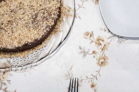 Part of a brown cake sprinkled with light brown chocolate. You can see the fork and part of the...