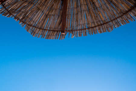 Part of the straw beach umbrellas and View of the beautiful blue sky with little cloudsの写真素材
