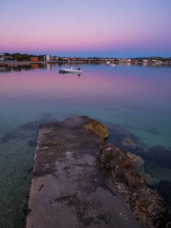 Dock, quay on island Vir, Croatia early in the morning. Dock and rubber boat overlooking beautiful purple and pink sky over Adriatic sea.の写真素材