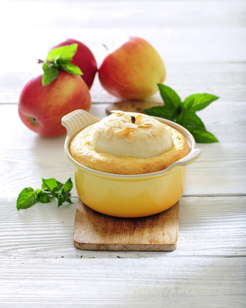 Baked apple sponge pudding cake with almonds on wooden table.の写真素材