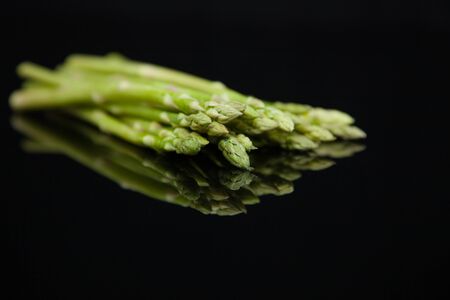 fresh asparagus on a black glass table with reflectionの写真素材