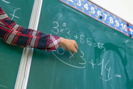 teacher writing math formula on blackboard in classroom, education concept