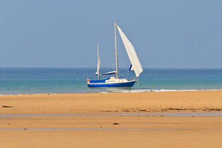 Blue Yacht anchored near sandy beach