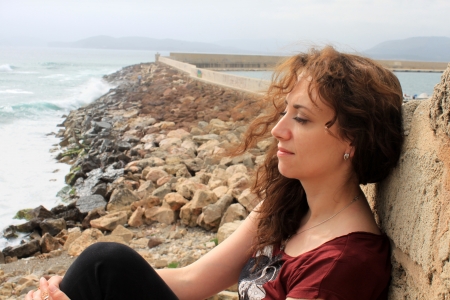 Beautiful young female relaxing with the sea in the background, Alghero, Sardinia, Italyの写真素材