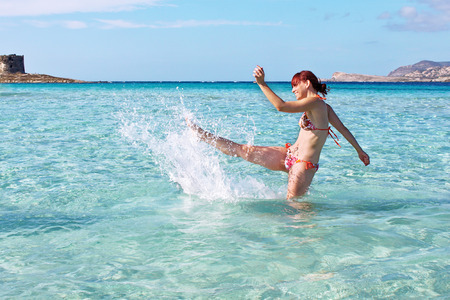Happy girl splashing the crystal clear sea, La Pelosa, Sardinia, Italy の写真素材