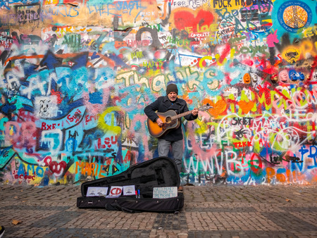 PRAGUE, CZECH REPUBLIC - FEBUARY 20, 2018: Street Busker performing Beatles songs in front of John Lennon Wall on Kampa Island.Old town near Charles Bridge.The Historical wall in Europe.のeditorial素材