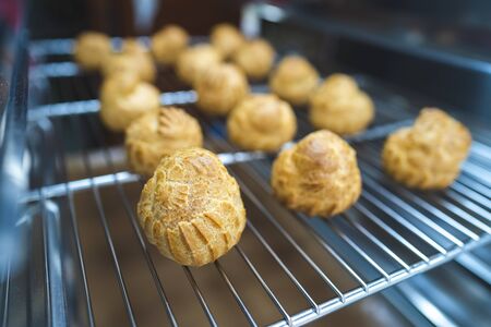 Close up choux baked home made  fresh crispy eclairs and profiteroles. Making desserts and sweets on...