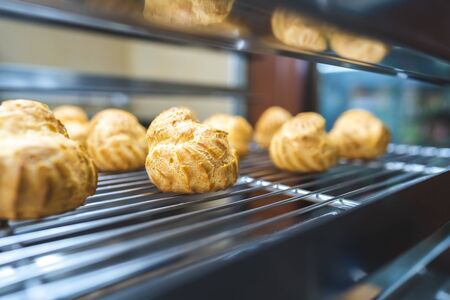 Close up choux baked home made  fresh crispy eclairs and profiteroles. Making desserts and sweets on an industrial scale, industry, background.Choux is a traditional french dessert.の写真素材