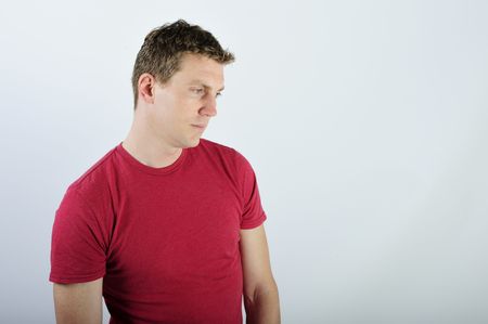 A young man is standing in a room.  He is looking away from the camera.  Horizontally framed shot.の写真素材