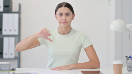 Thumbs Down by Young Latin Woman in Officeの写真素材