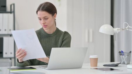 Paperwork by Young Woman with Laptop and Documentsの写真素材