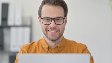Close Up of Young Man with Laptop Smiling at the Cameraの写真素材