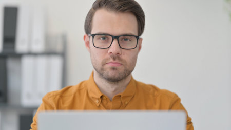 Close Up of Young Man with Laptop Looking at the Cameraの写真素材
