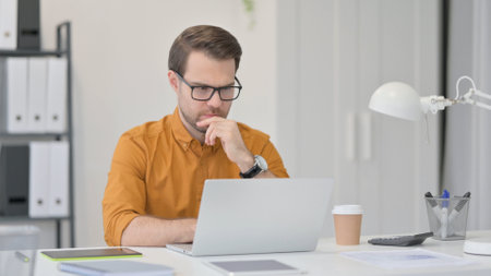 Young Man with Laptop, Thinking in Officeの写真素材