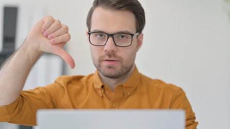 Close Up of Thumbs Down by Young Man with Laptopの写真素材