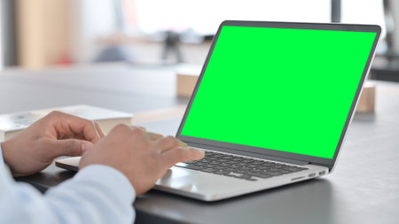 African Man Typing on Laptop with Green Chroma Key Screenの写真素材