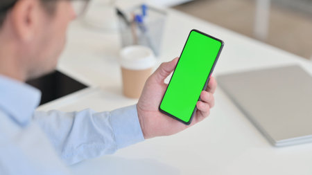 Man using Smartphone with Green Chroma Screen in Officeの写真素材