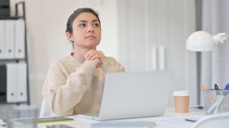 Young Indian Woman Thinking using Laptopの写真素材