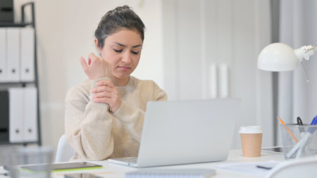 Young Indian Woman with Laptop having Wrist Painの写真素材